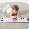 Taf Toys pehme=C3=A4 ensikirja 3 in 1 taaperolla lattialla. - Kuvakirjat - 226263 - 3