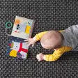 Taf Toys ensikirja Sensory book What does Paul Wear lapsella lattialla=
=2E - Kuvakirjat - 248916 - 2